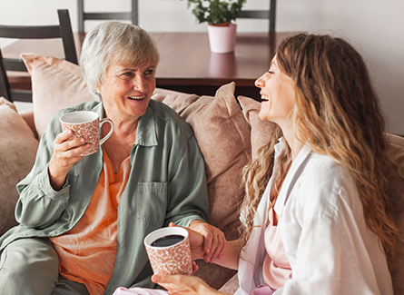 Older woman sitting with daughter on coach