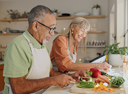 Happy older couple chopping vegetables
